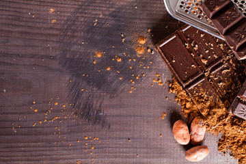 Chocolate products. Chocolate, cocoa beans, cocoa and nuts on wooden background. 