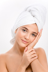 Lovely woman with towel on head touching face skin