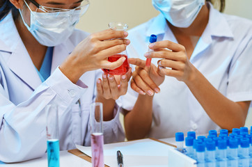 close up of scientists examining and comparing chemicals in laboratory
