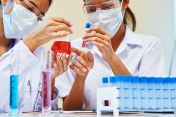 close up of scientists examining and comparing chemicals in laboratory
