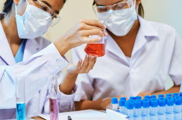 close up of scientists examining and comparing chemicals in laboratory
