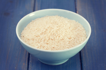 raw rice on blue bowl on blue wooden background