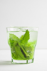 Green cocktail with kiwi slices on white wooden background