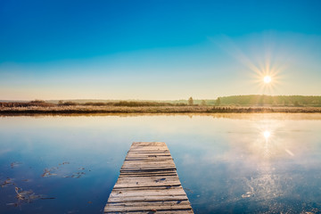 Old wooden boards pier on Calm Water Of Lake, River