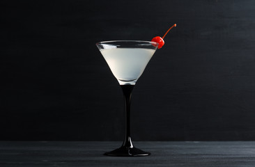 Cocktail in martini glass on the black wooden background