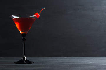 Cocktail in martini glass on the black wooden background
