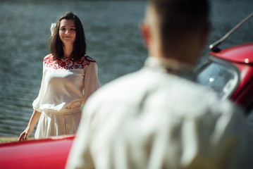 beautiful bride and elegant stylish groom posing near retro car