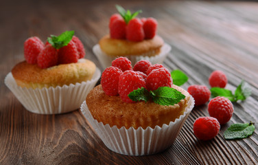 Delicious cupcakes with berries and fresh mint on wooden table close up