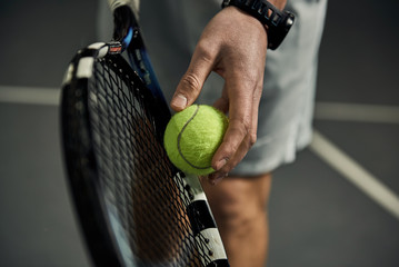 Close-up of male hand holding tennis ball and racket. Professional tennis player starting set.  - obrazy, fototapety, plakaty