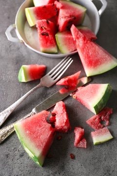 Sliced watermelon in metal bowl on grey background, close up
