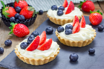 Homemade shortbread tartlets with custard cream, strawberry and blueberry