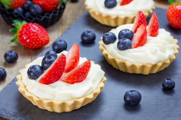 Homemade shortbread tartlets with custard cream, strawberry and blueberry