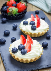 Homemade shortbread tartlets with custard cream, strawberry and blueberry