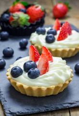 Homemade shortbread tartlets with custard cream, strawberry and blueberry