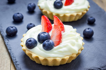 Homemade shortbread tartlets with custard cream, strawberry and blueberry