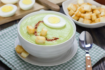 Cream soup with avocado, garnished with egg and croutons. Healthy eating.