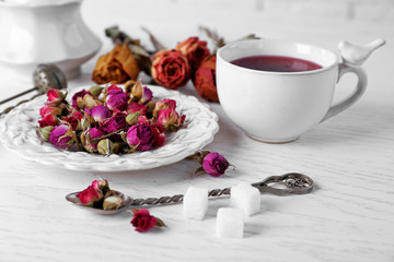 Tea and tea rose flowers on table closeup