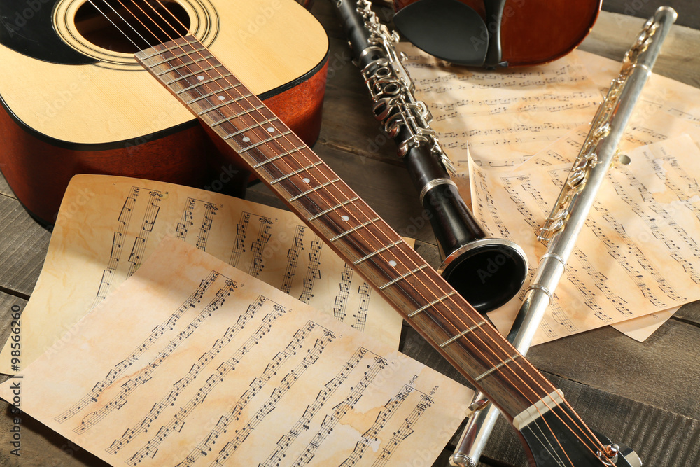 Wall mural acoustic guitar, soprano saxophone, violin, flute and note sheets on wooden background