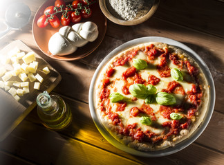 Pizza with tomatoes mozzarella and basil on the wooden table