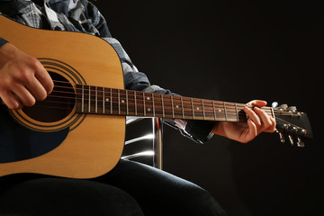 Fototapeta na wymiar Musician plays guitar on black background, close up