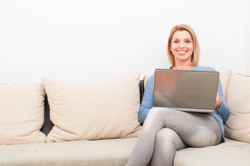 Smiling woman using laptop at home on the couch