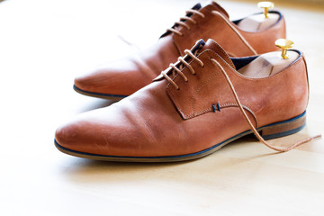 Brown leather shoes with wood shoe forms on wooden table