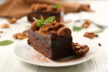 Piece of chocolate cake with walnut and mint on the table, close-up