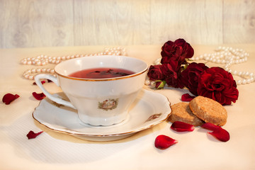 Obraz na płótnie Canvas Cup of tea with roses and cake on white background 