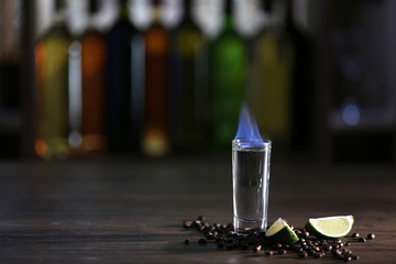 Burning cocktail with lime and coffee beans on table in a bar