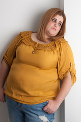 Sad overweight woman leaned against a wall