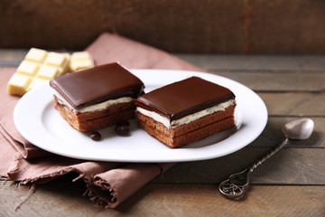 Delicious chocolate brownies on plate, on wooden background