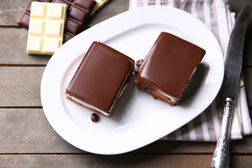 Delicious chocolate brownies on plate, on wooden background