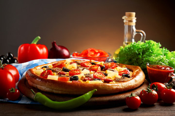 Delicious pizza with vegetables and meat on brown background