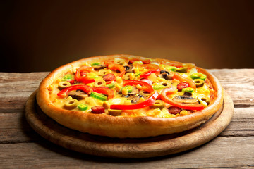 Delicious pizza with vegetables on brown background