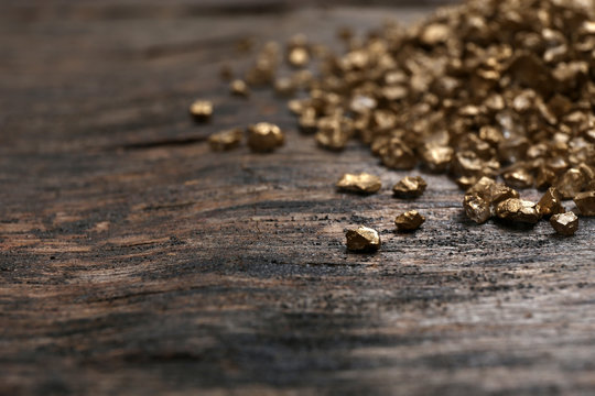 A pile of Gold nugget grains, on wooden background