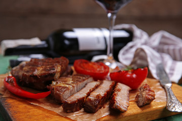 Roasted beef fillet and vegetables on cutting board, on wooden background