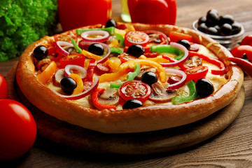 Delicious pizza with vegetables, on wooden table, close-up