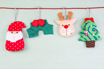 Christmas doll ornament hanging  with rope on green wood backgro