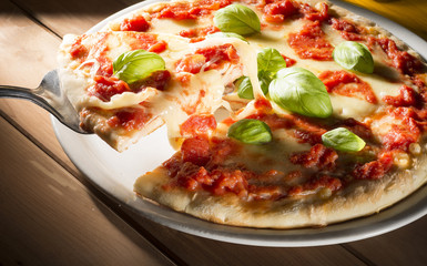 Pizza with tomatoes mozzarella and basil on the wooden table