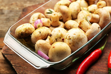 Marinating mushrooms with spices on wooden table