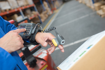Man in warehouse wearing handheld scanner and computer © auremar