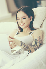 Young woman using laptop on bed