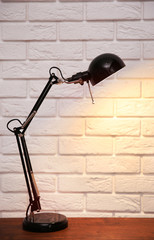 Modern lamp on table on brick wall background