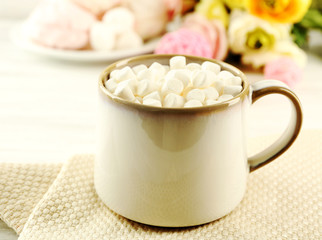 Mug of hot chocolate with marshmallows, on light wooden background