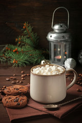 Mug of hot chocolate with marshmallows, fir tree branch on wooden background