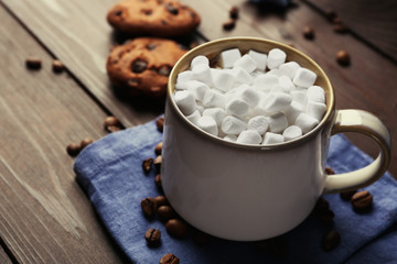Mug of hot chocolate with marshmallows, on wooden background