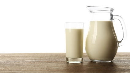 Milk in glass and in jar on table isolated on white background