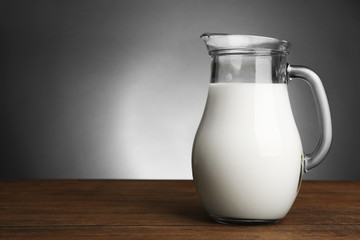 Jar of milk on wooden table on dark background