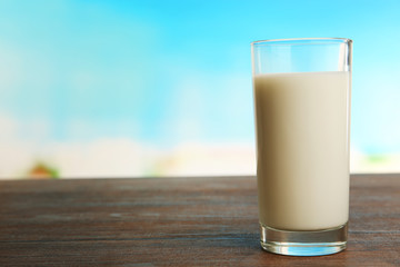 Glass of milk on table on blurred natural background