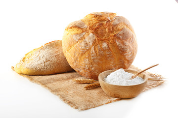 Bread bread with ears and flour on napkin isolated on white